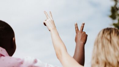 woman in white and pink floral shirt raising her hands