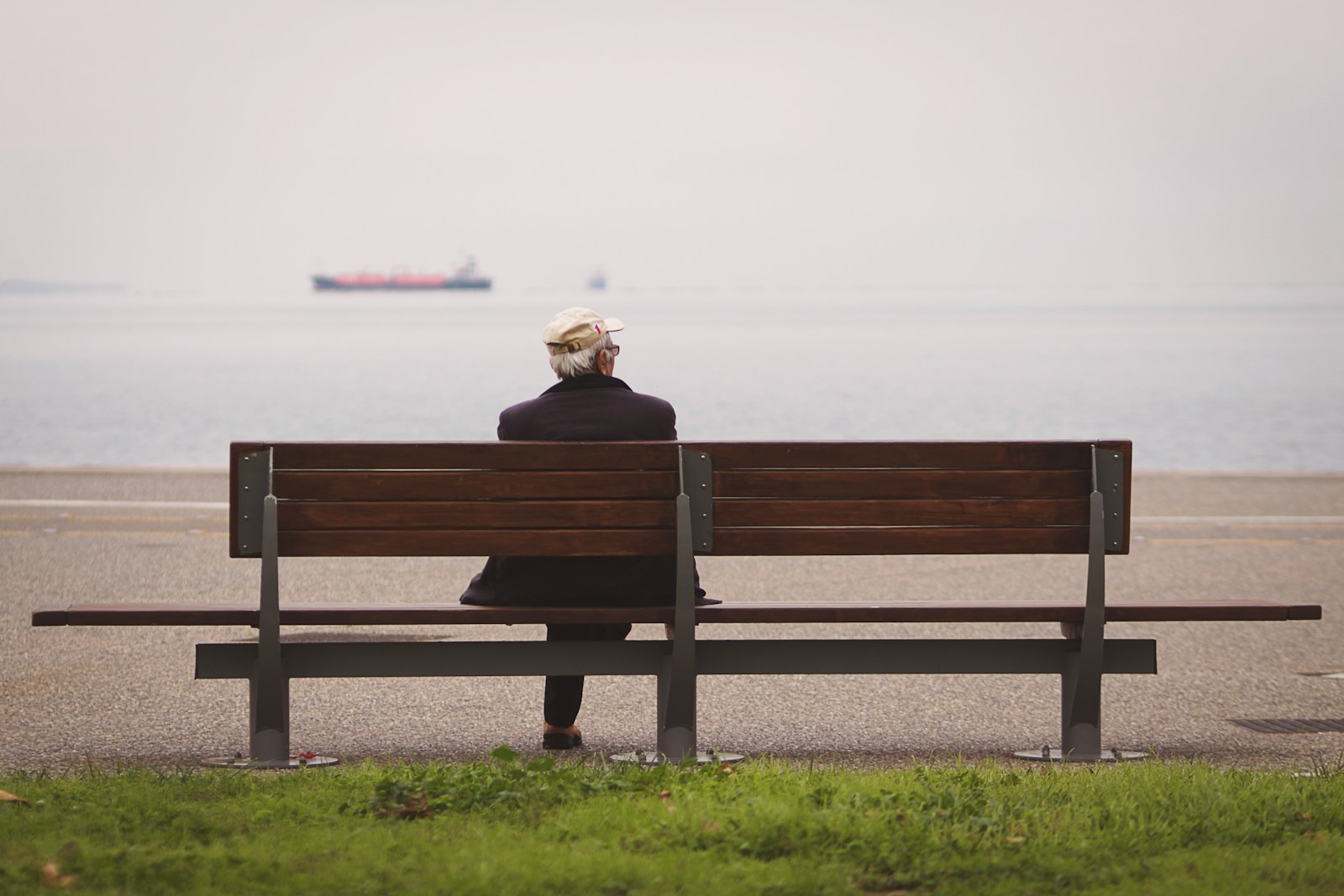 man sitting on brown bench facing on the sea